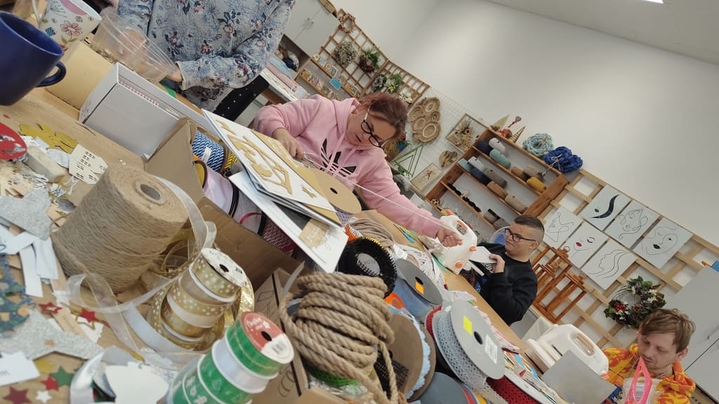 Uczestnicy pracowni rękodzieła tworzą ozdoby i dekoracje przy stole