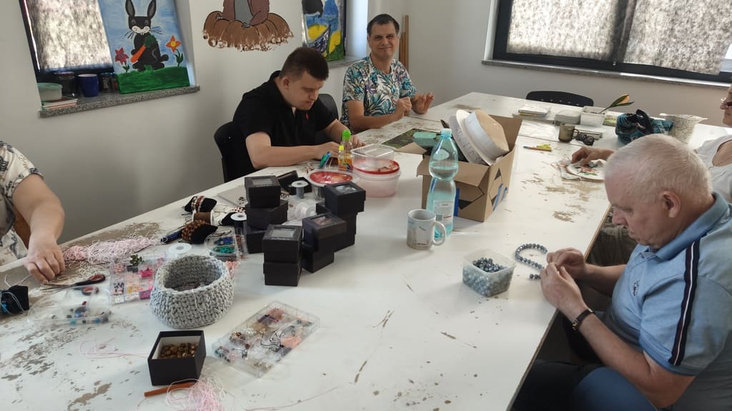 Zajęcia grupowe – uczestnicy robią rękodzieło przy wspólnym stole